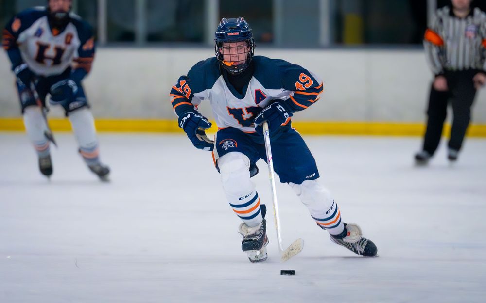 Hershey Trojans skater carries the puck up ice at IceWorks in the Flyers Cup Quarterfinals by SportsFox Photography, Hershey PA.