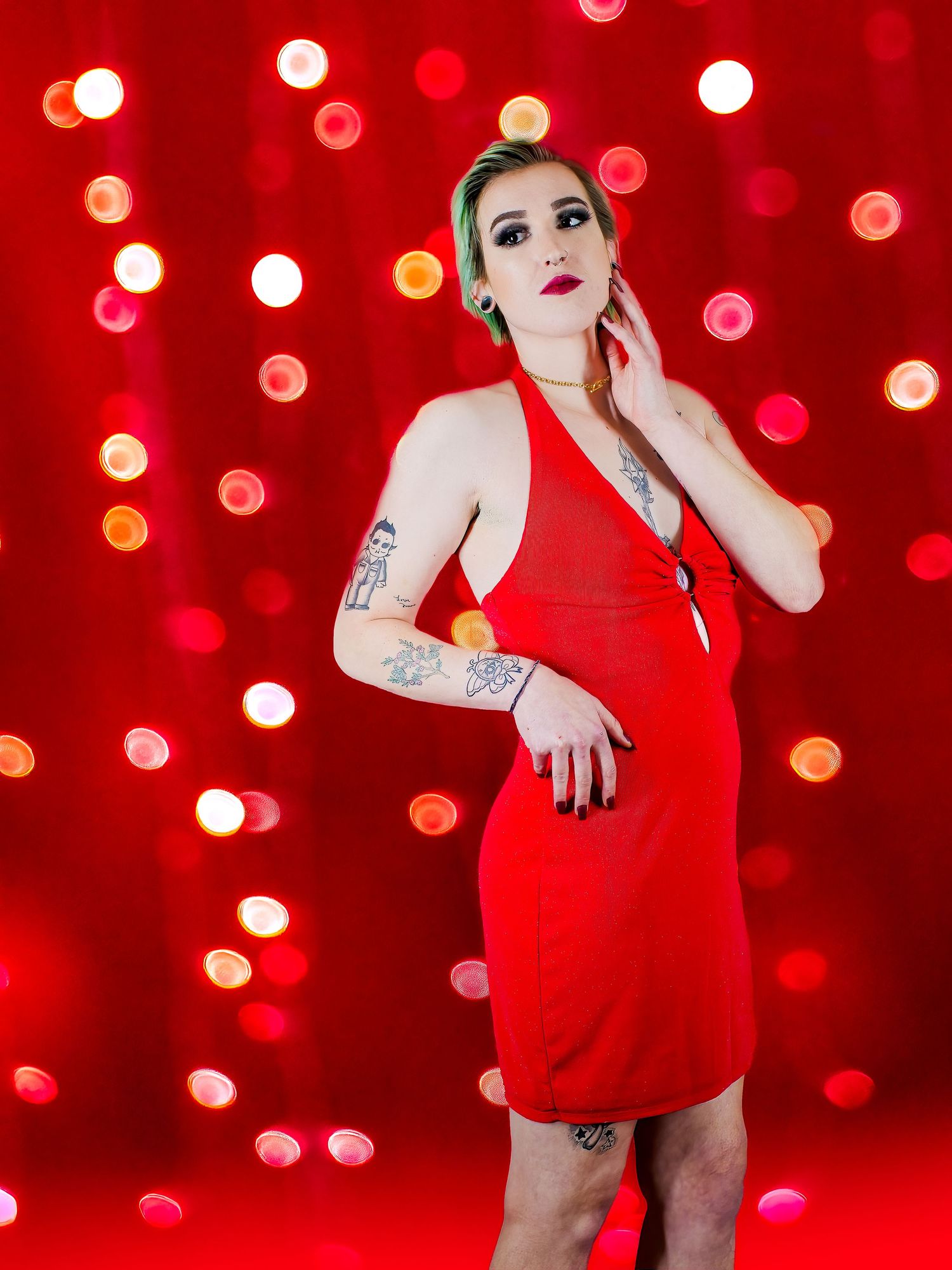 Figure in red dress poses against vibrant red bokeh light background.