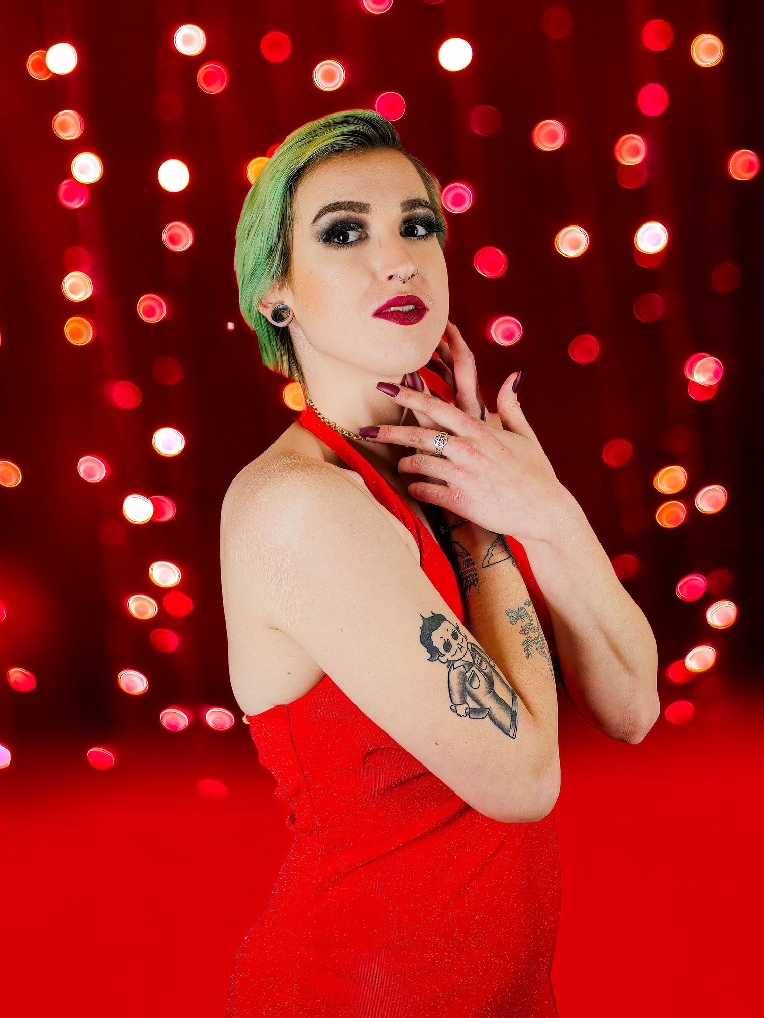 Artistic portrait against red bokeh background with dramatic lighting and styling.