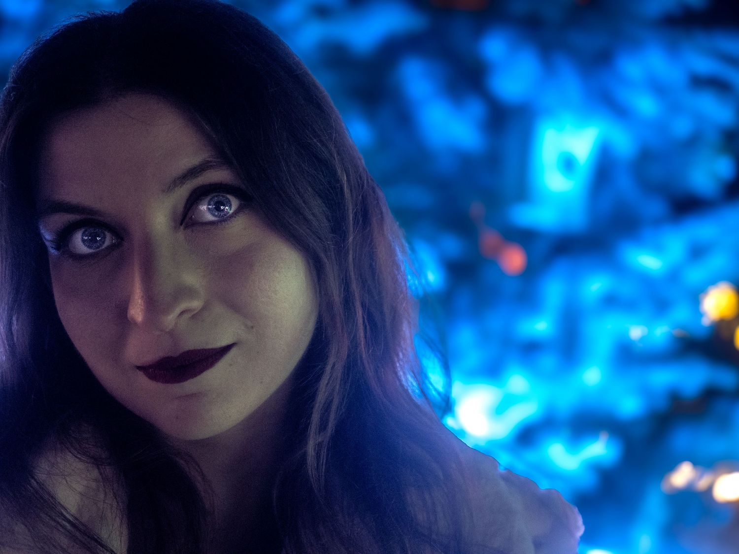 Moody portrait with dramatic blue lighting creates mysterious atmosphere.