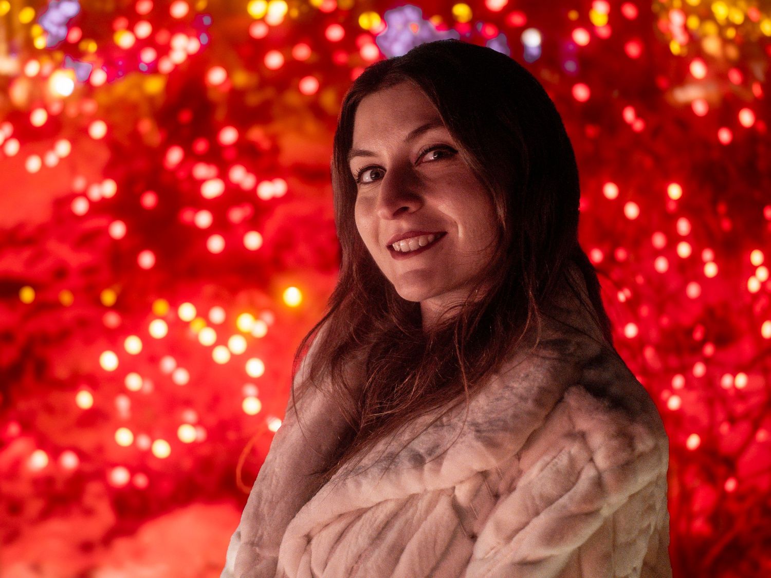 Portrait with red bokeh lights creating warm festive atmosphere.