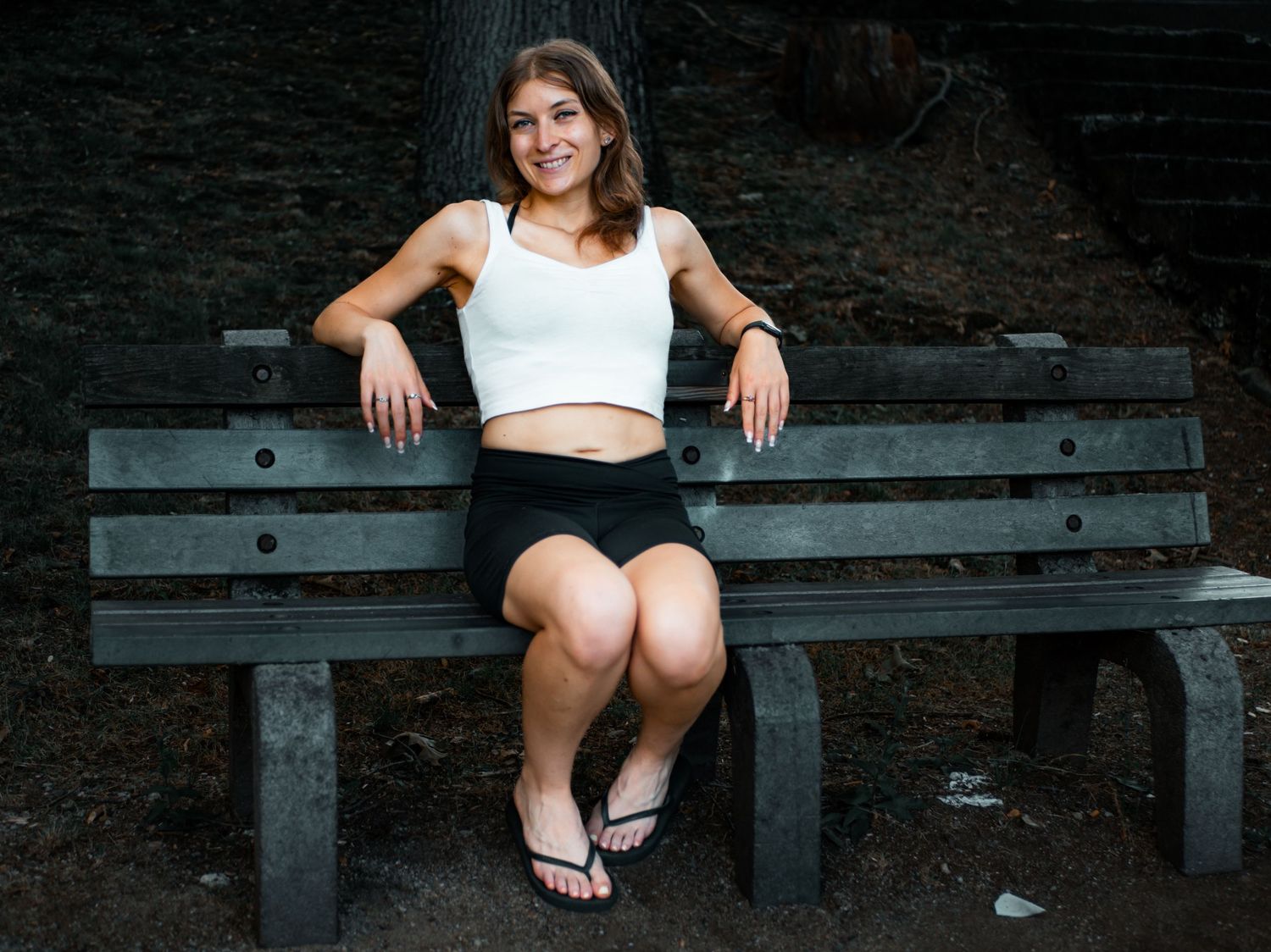 Someone sitting on a wooden park bench surrounded by trees and natural scenery.