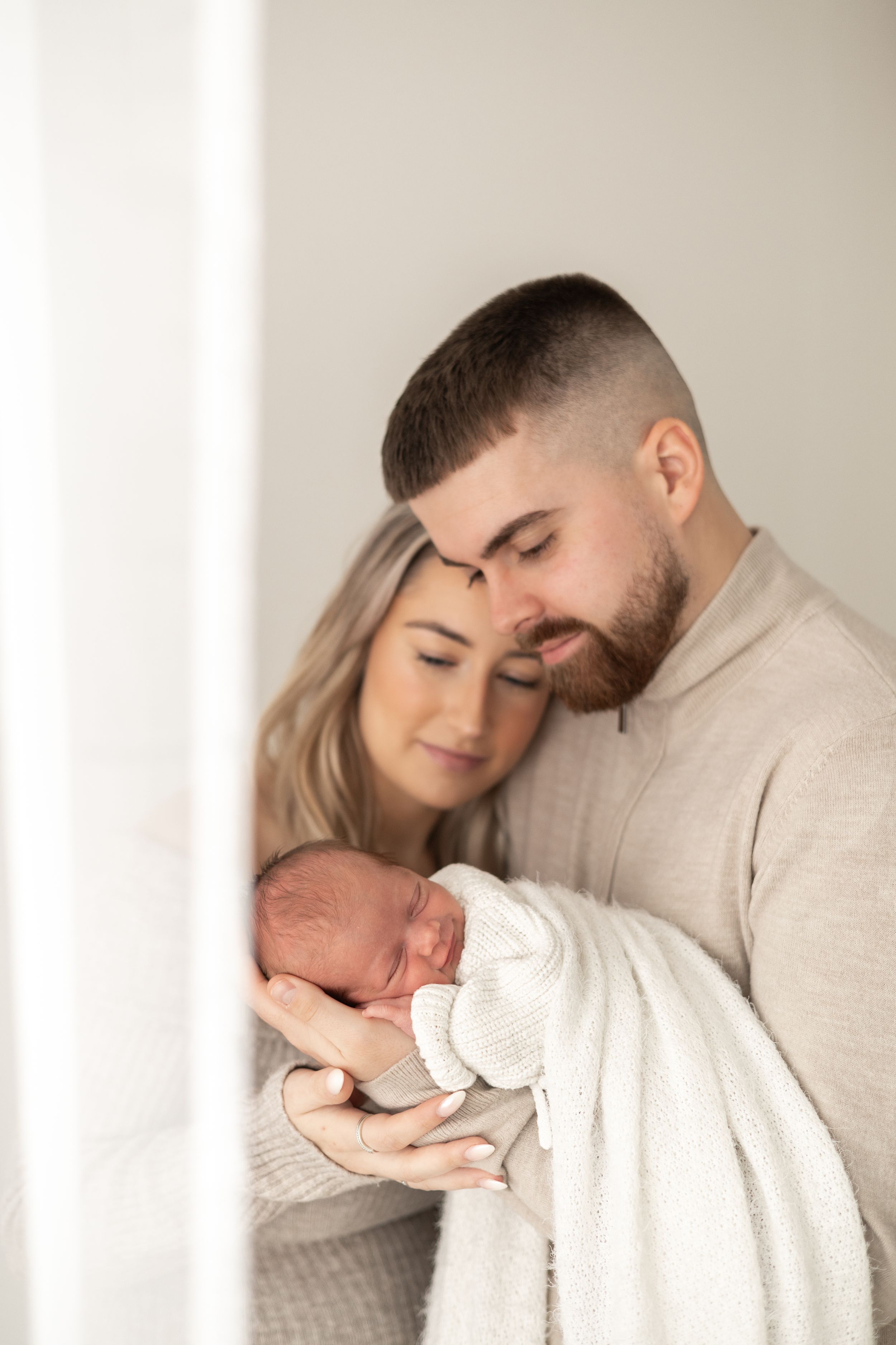 New parents tenderly cradling their sleeping newborn baby photographer Nottingham studio session