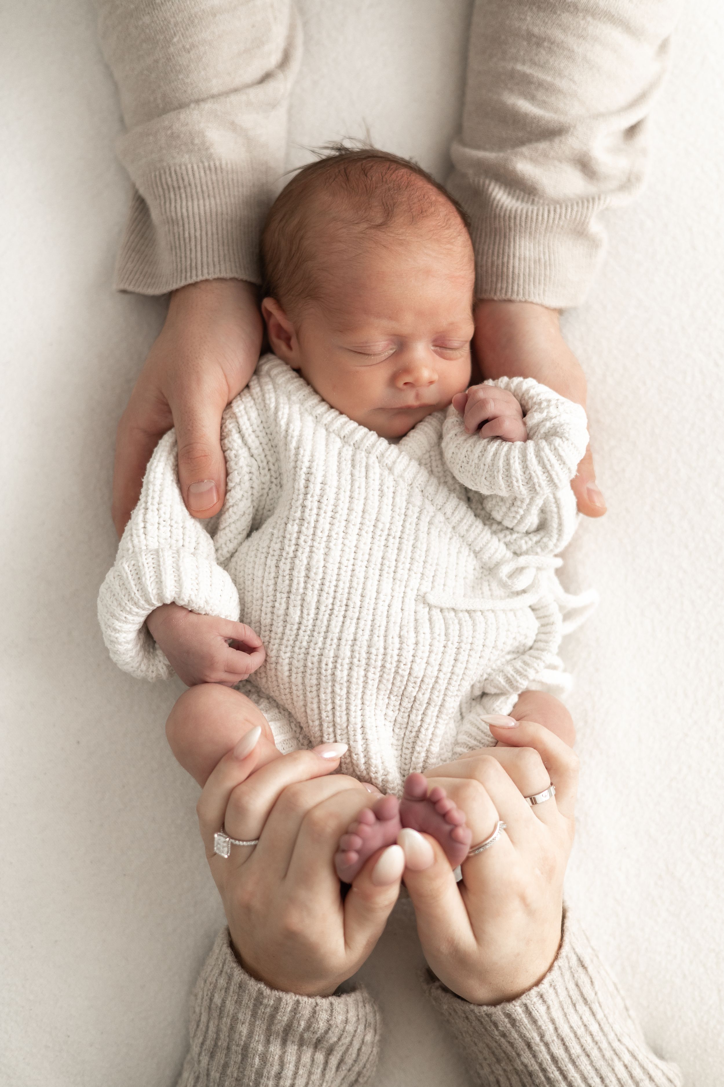Newborn baby sleeping peacefully in parents hands, baby photographer Nottingham studio session