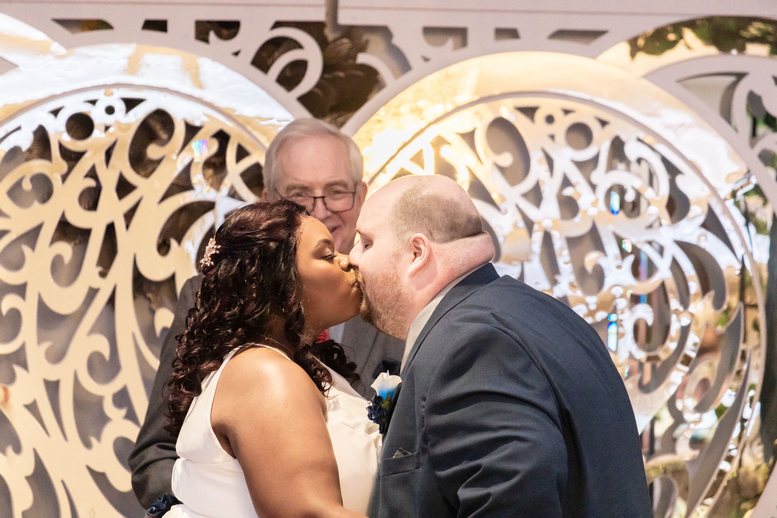 Zeus Holbrook San Diego Wedding Photographer captutres first kiss of a couple infront of a giant gold heart