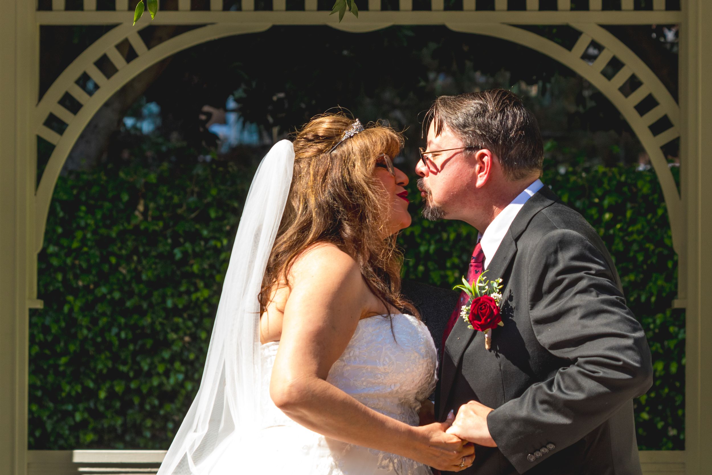 Bride and groom sharing a kiss under a garden arch at the Disneyland Hotel by Zeus Holbrook San Diego Wedding Photographer