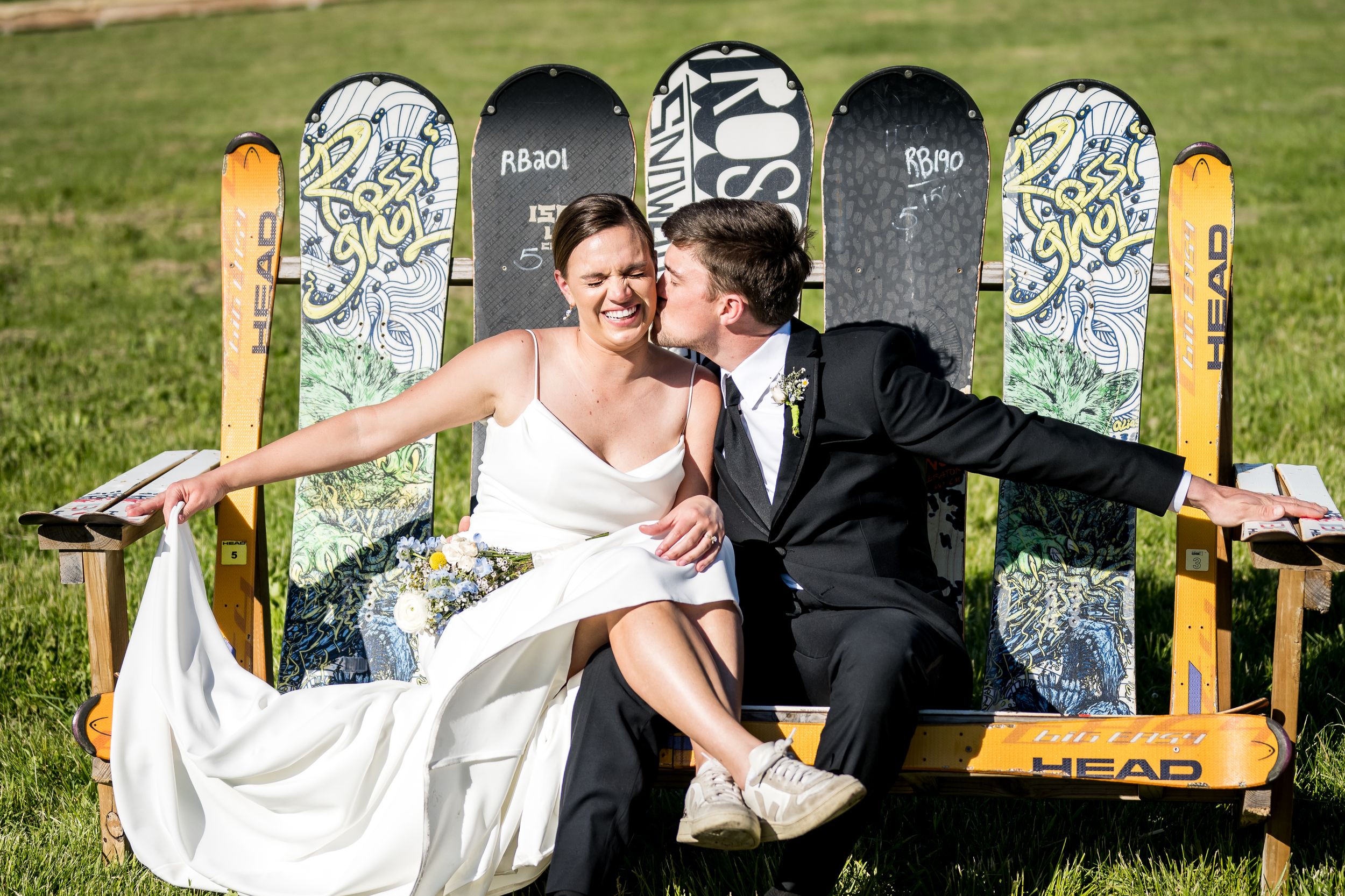 Newlyweds share romantic moments on a stone balcony surrounded by autumn foliage and hanging floral decorations.