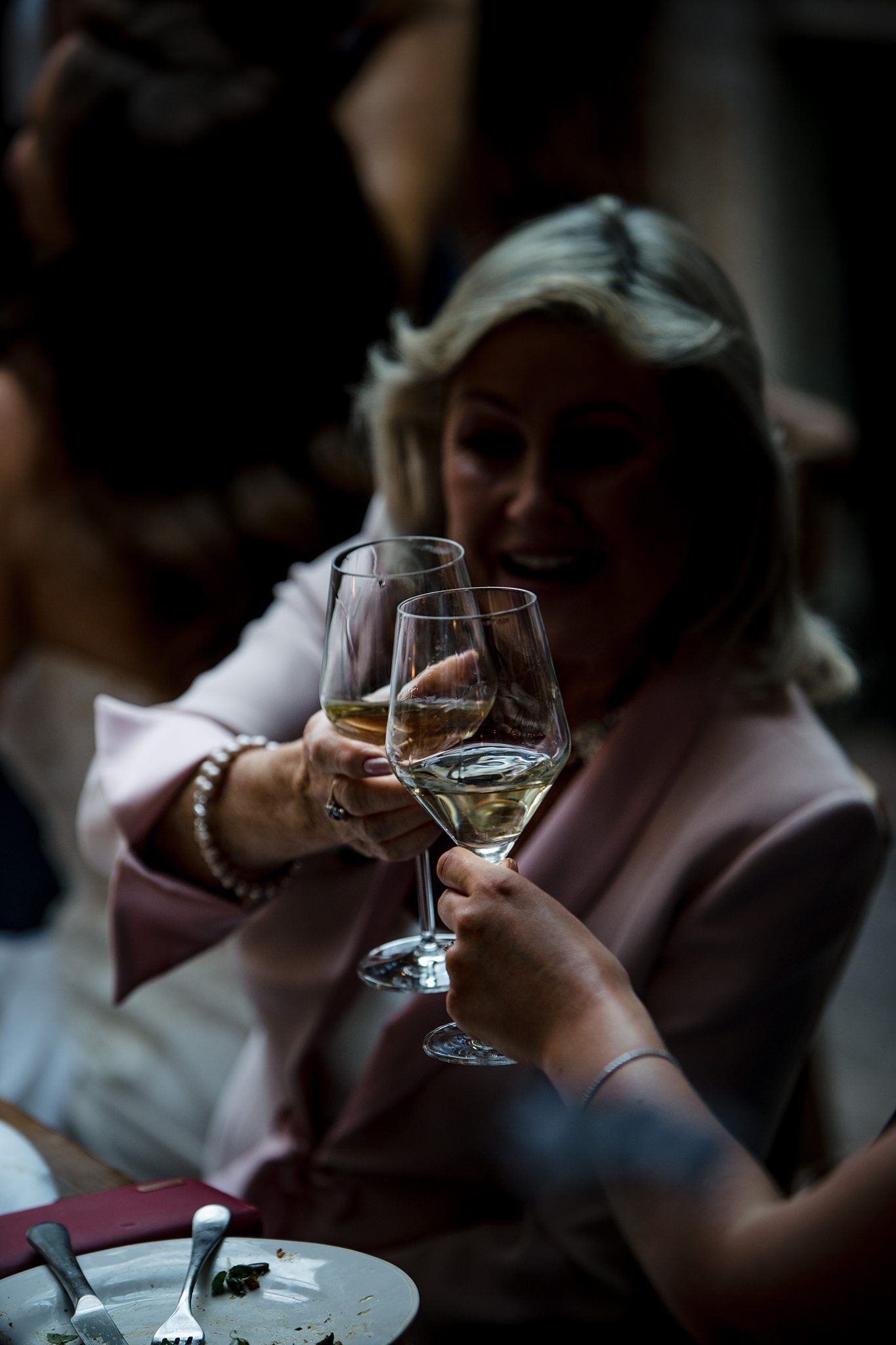 A person holds a delicate wine glass in a dimly lit setting during a wedding at Lightfoot & Wolfville