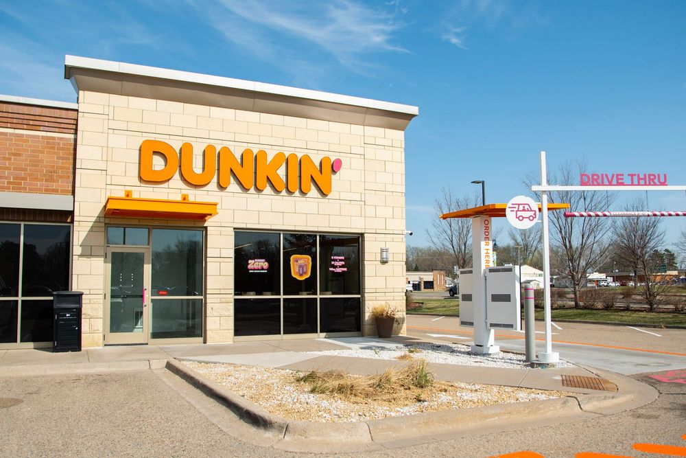 Dunkin' Donuts restaurant exterior with drive-thru lane on a sunny day.