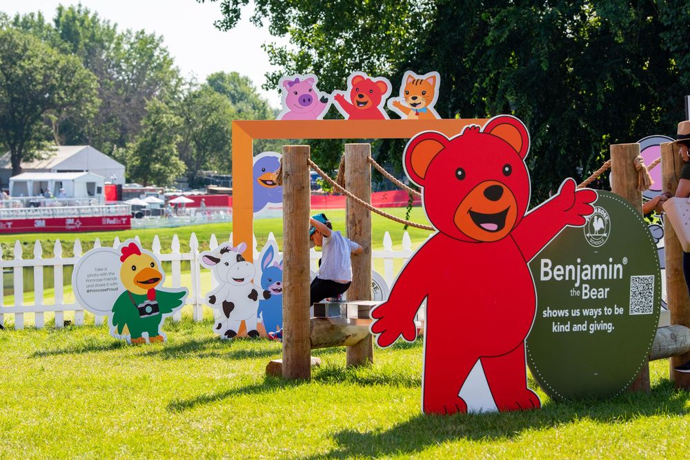 Colorful cartoon character cutouts and decorations displayed on a sunny lawn for an outdoor children's event.