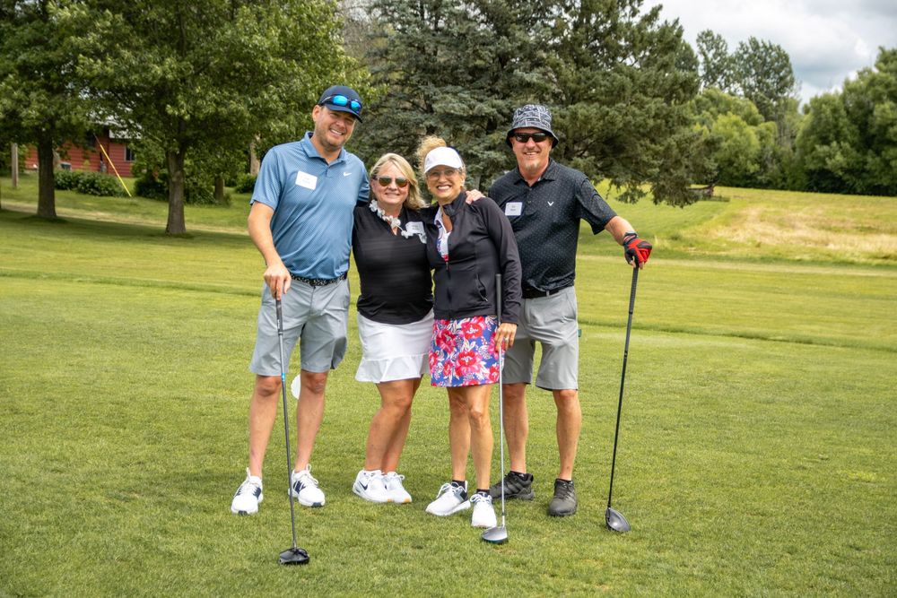 Golfers practicing their putting skills on a sunny day at a green grassy golf course.