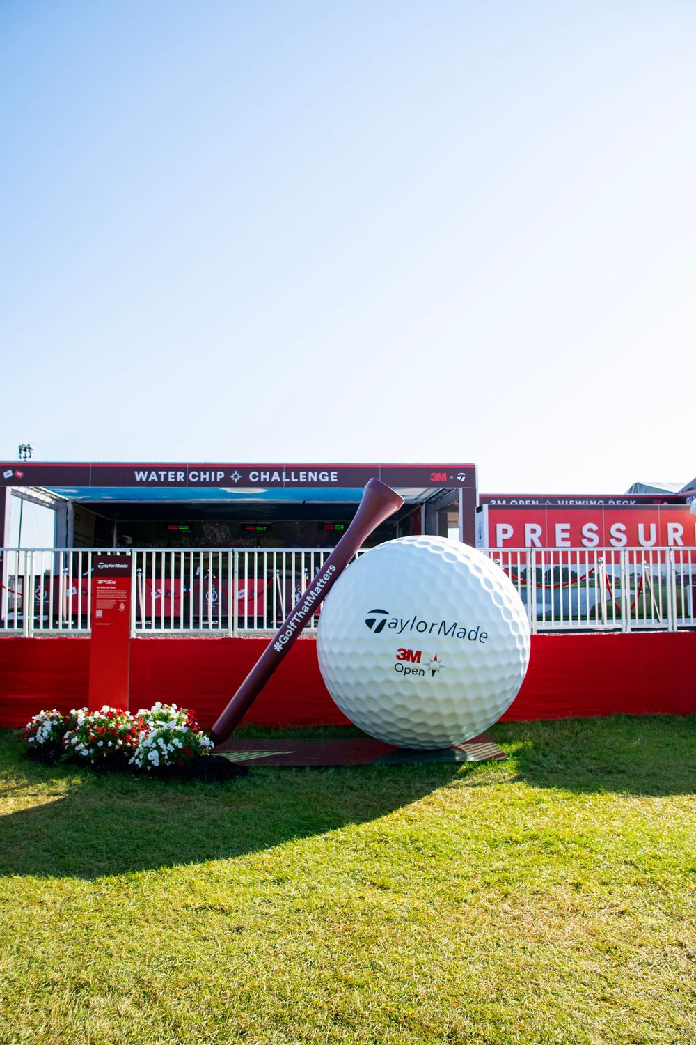 Giant golf balls on display at a golf tournament with red signage and green grass in the background.