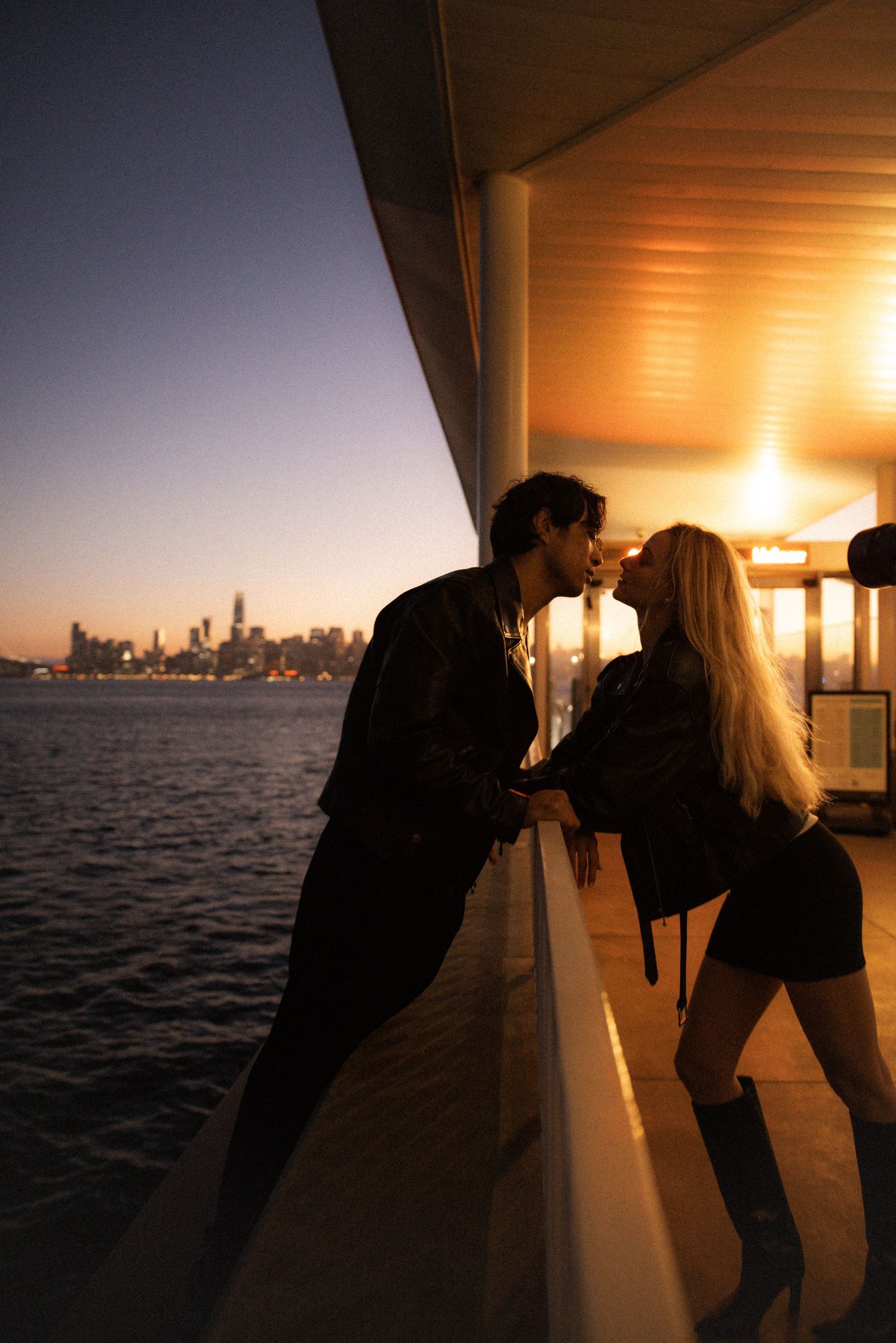 Couple sharing a romantic moment at sunset with the Bay Bridge and San Francisco skyline in the background.