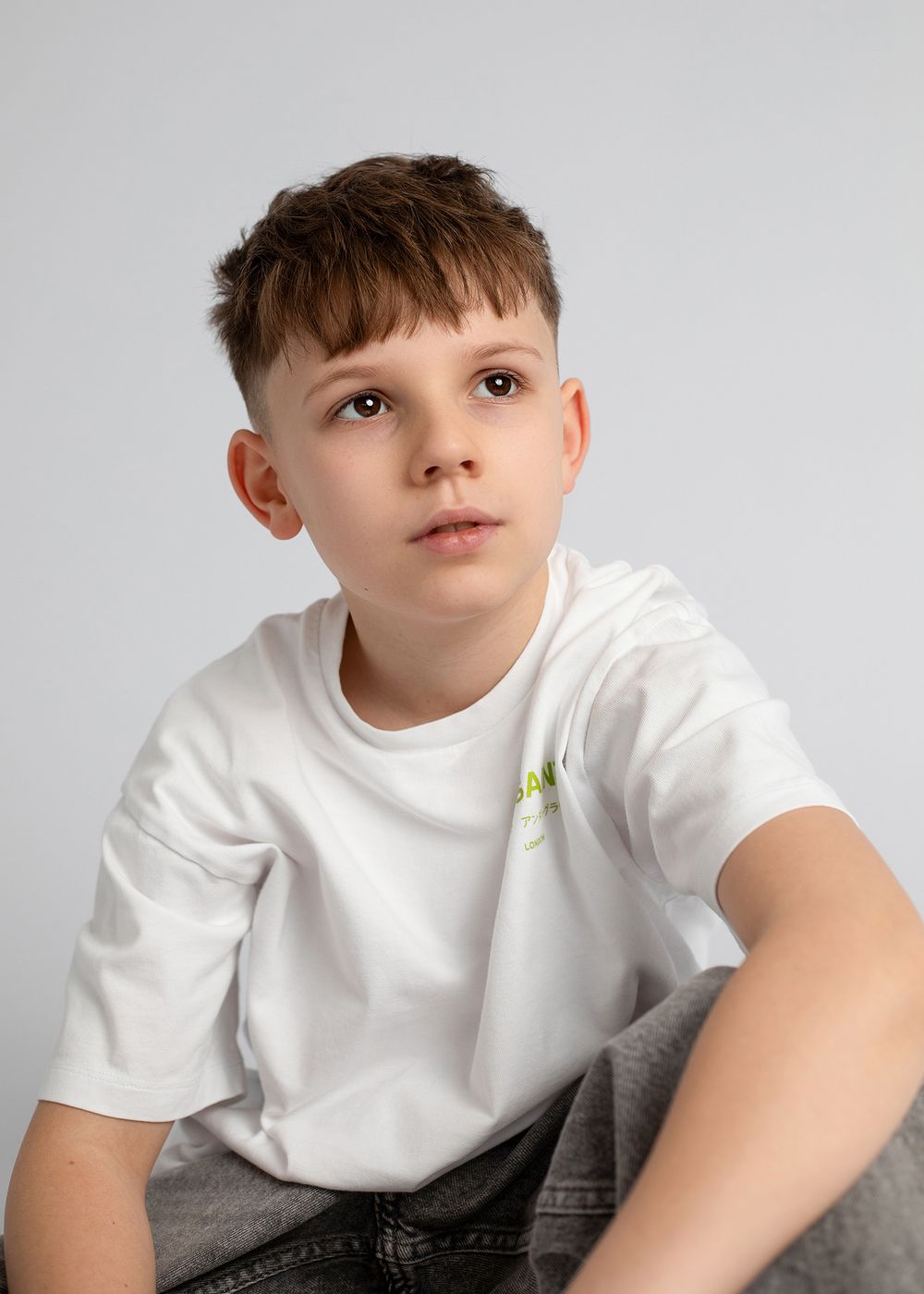 Young person in white t-shirt poses against gray background in series of connected profile shots.