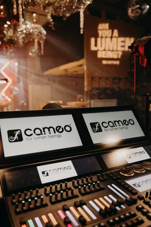 Cameo lighting control panels with illuminated displays in professional audio setup.