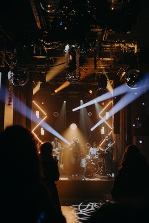 Concert stage with dramatic lighting beams cutting through smoke in dark performance space.