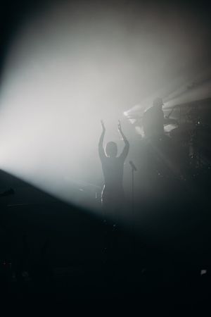 Silhouetted performers on misty stage with dramatic backlighting effects.