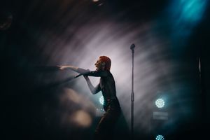 Dynamic performance shot with singer in silhouette against atmospheric stage lighting.