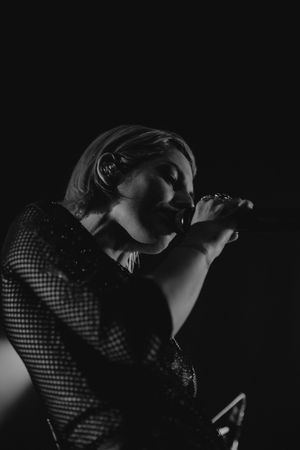 Black and white close-up of performer singing into microphone.