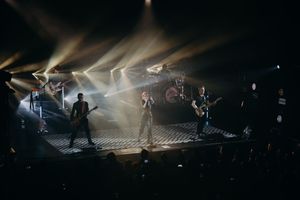 Full band performing on stage with dramatic beam lighting effects.