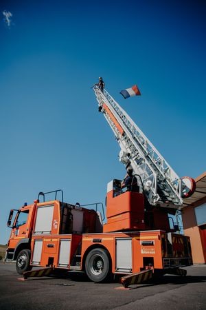 Line of bright orange fire trucks with extended ladders parked under clear blue sky.