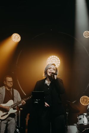 Band performing on stage with dramatic warm lighting and spotlights.