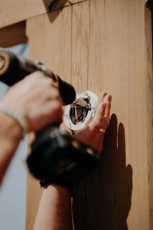 Close-up shot of hands installing or adjusting hardware on a wooden surface.