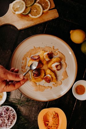 Plated dessert with citrus slices and garnishes being prepared on rustic wooden surface.