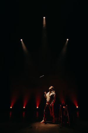 Silhouetted stage performance with dramatic red uplighting and theatrical spotlights.