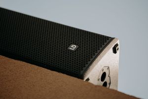 Close-up detail of black textured speaker equipment against gray background.