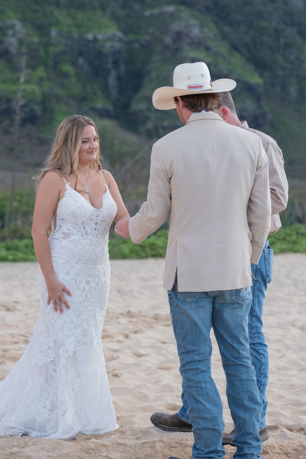 Bride and groom sharing a quiet moment during a beach wedding ceremony with mountains in the background.