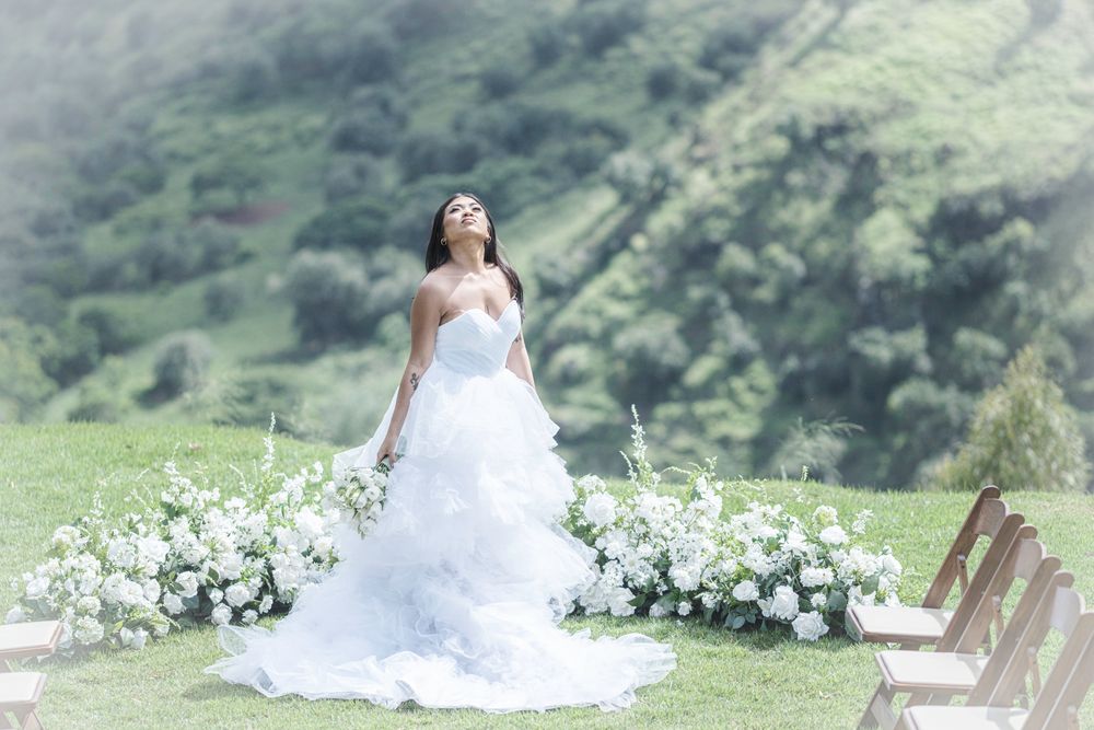 Bride standing among floral arrangements during an outdoor mountain wedding in Hawaii.