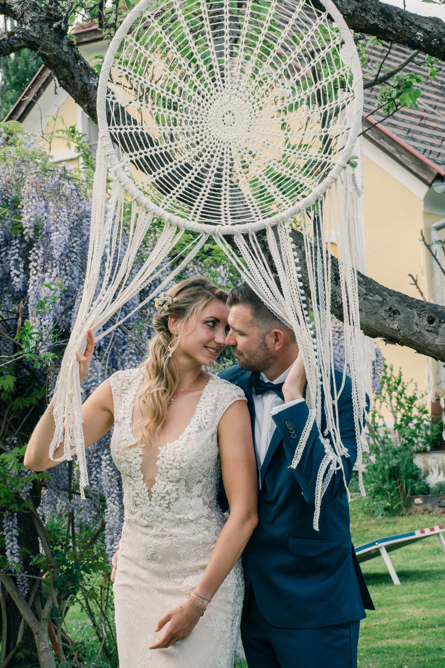 A dreamy outdoor wedding setting with a large macrame dreamcatcher and floral decorations.