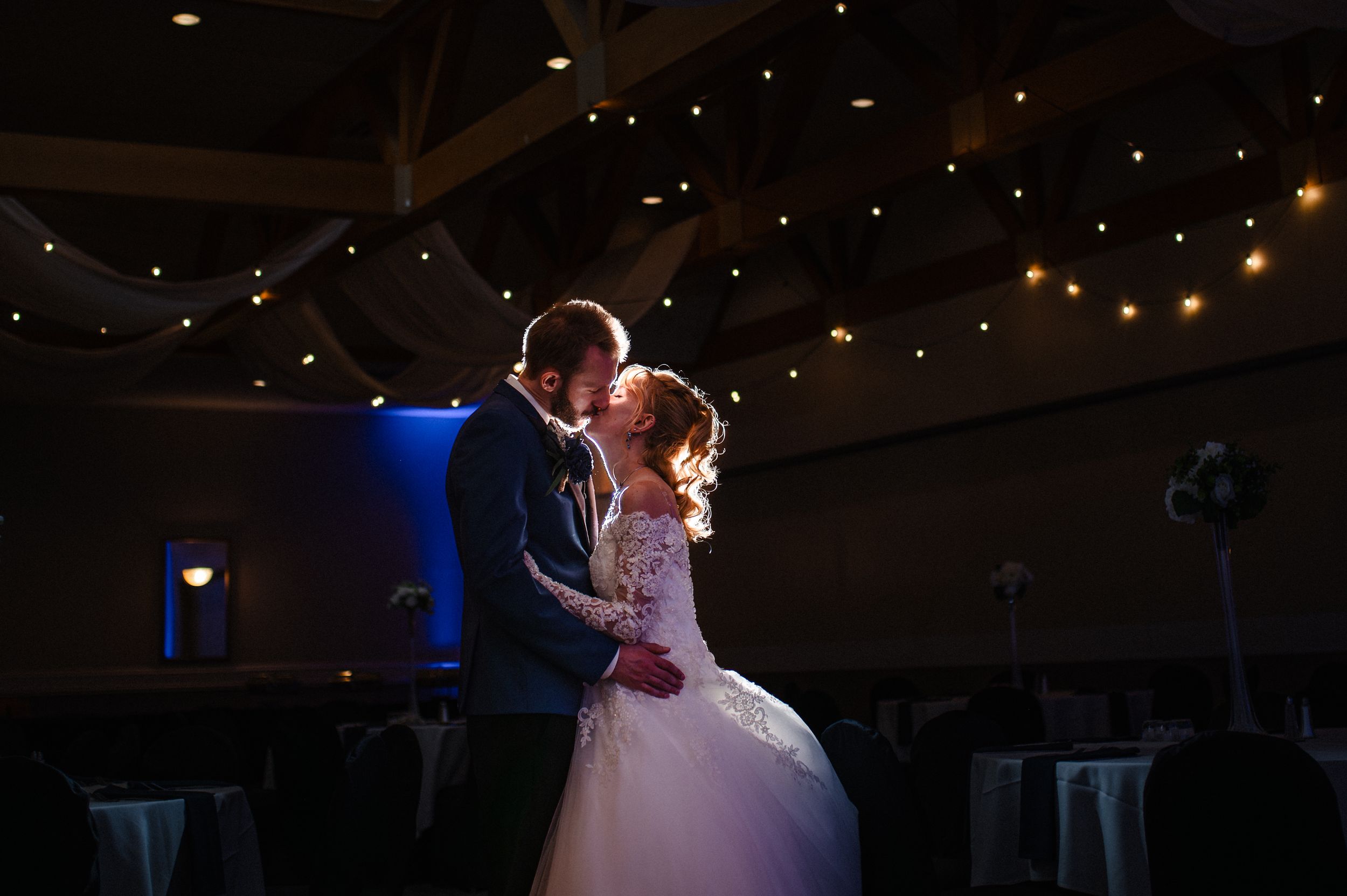 A couple shares their first dance as newlyweds under twinkling lights in a romantic reception venue.