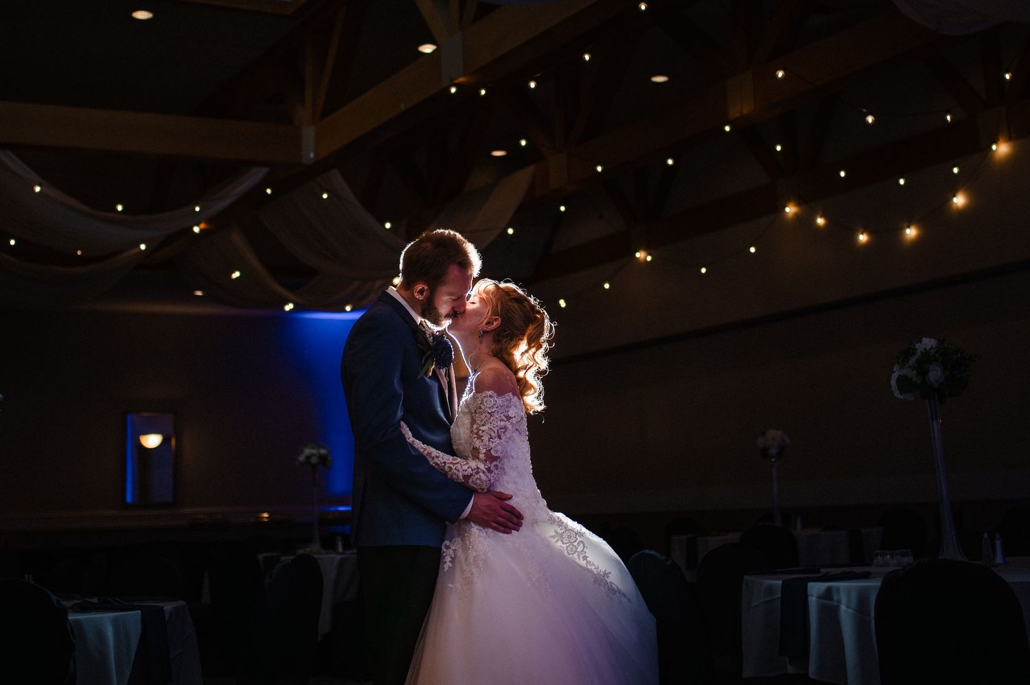 A couple shares their first dance as newlyweds under twinkling lights in a romantic reception venue.