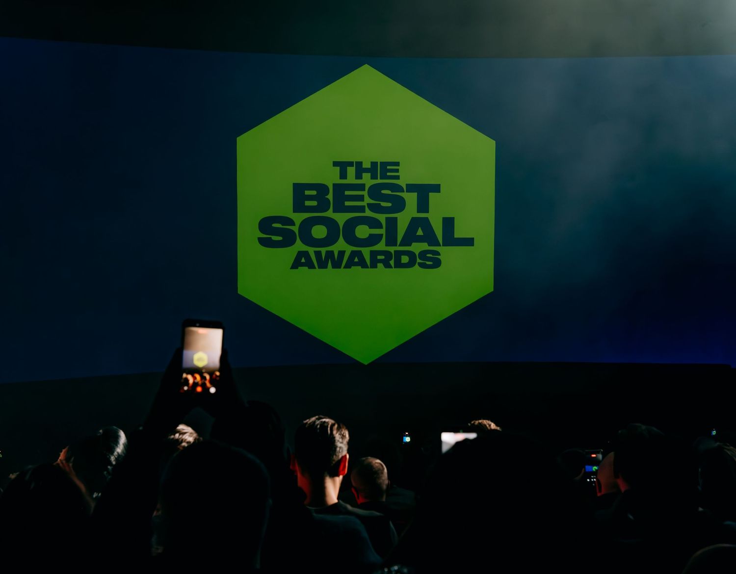 The Best Social Awards logo displayed on a large green hexagonal screen before a dark audience.
