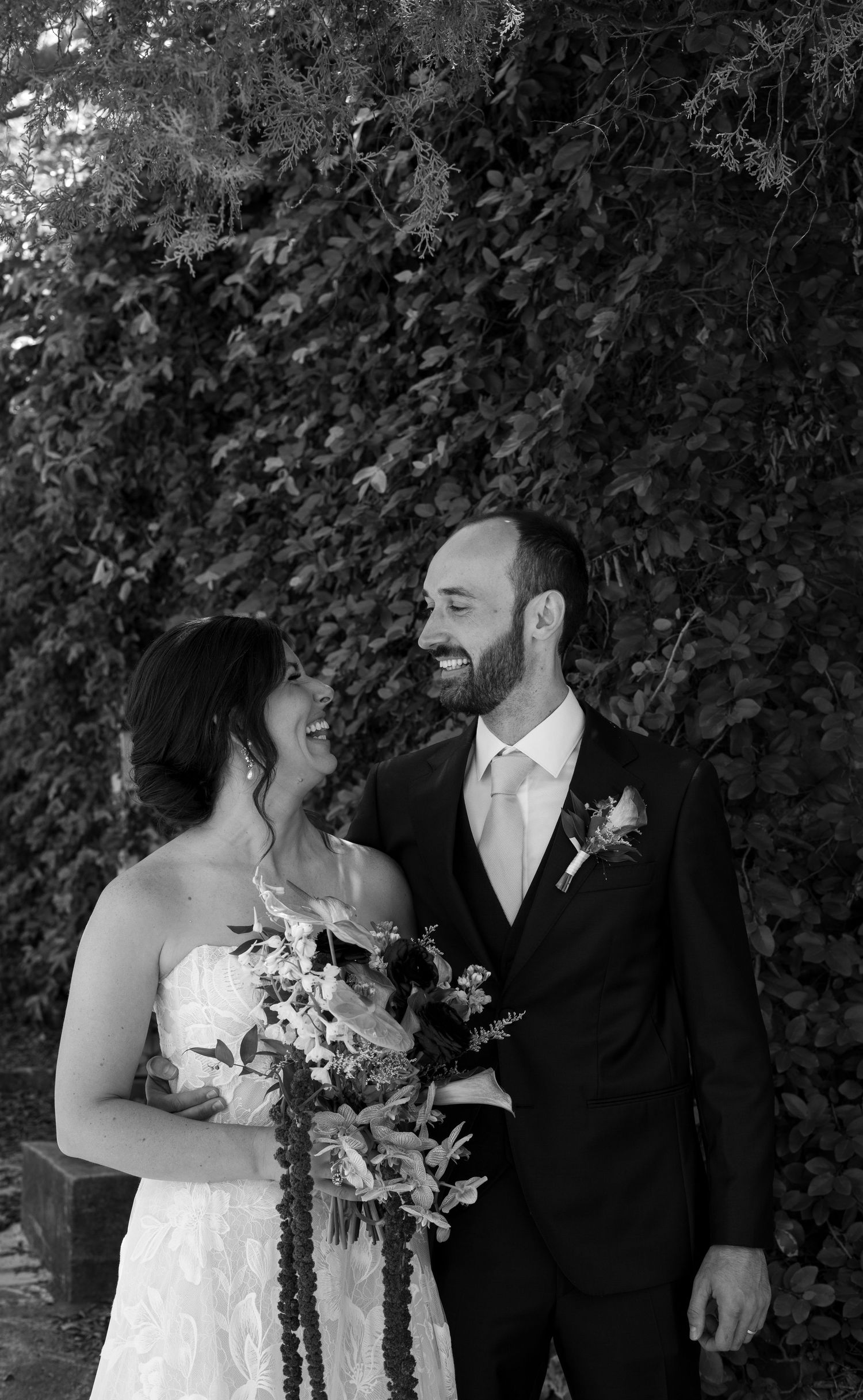 A couple shares a romantic moment in an elegant wedding venue, the bride in a white gown with veil, groom in a black tuxedo.