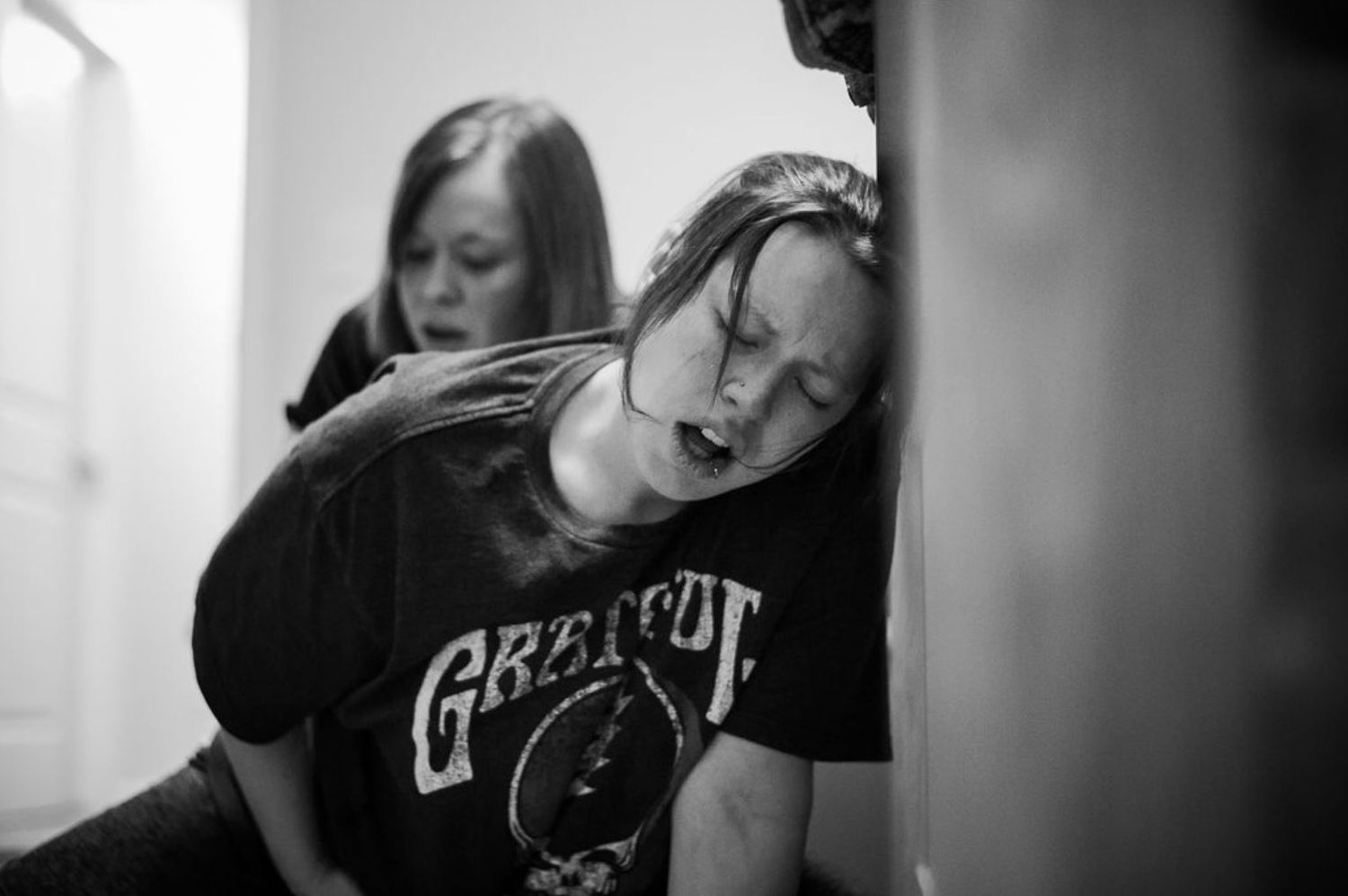 A dark monochrome image showing support during labor in a home setting.