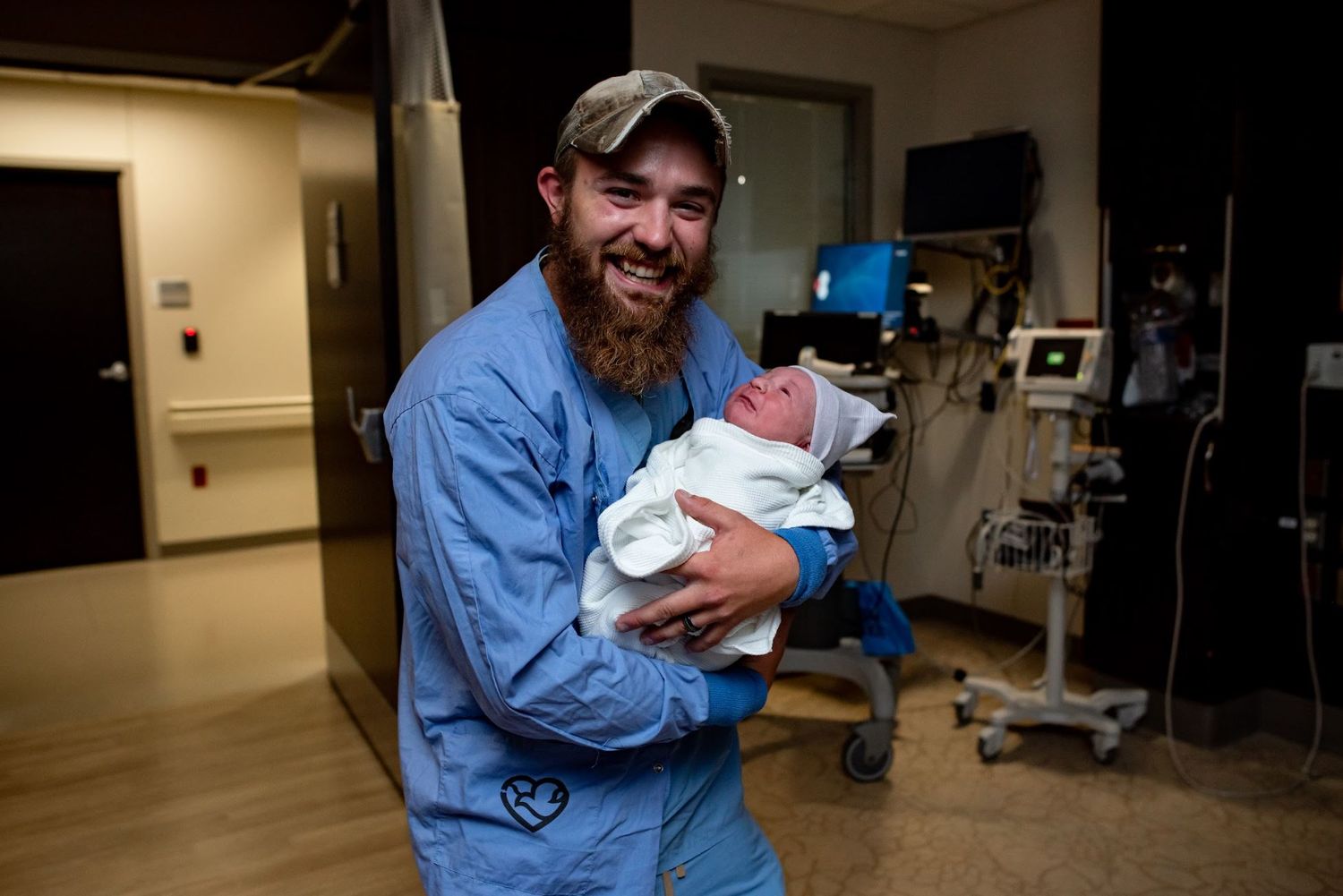 A joyful moment with a swaddled newborn in a hospital room.