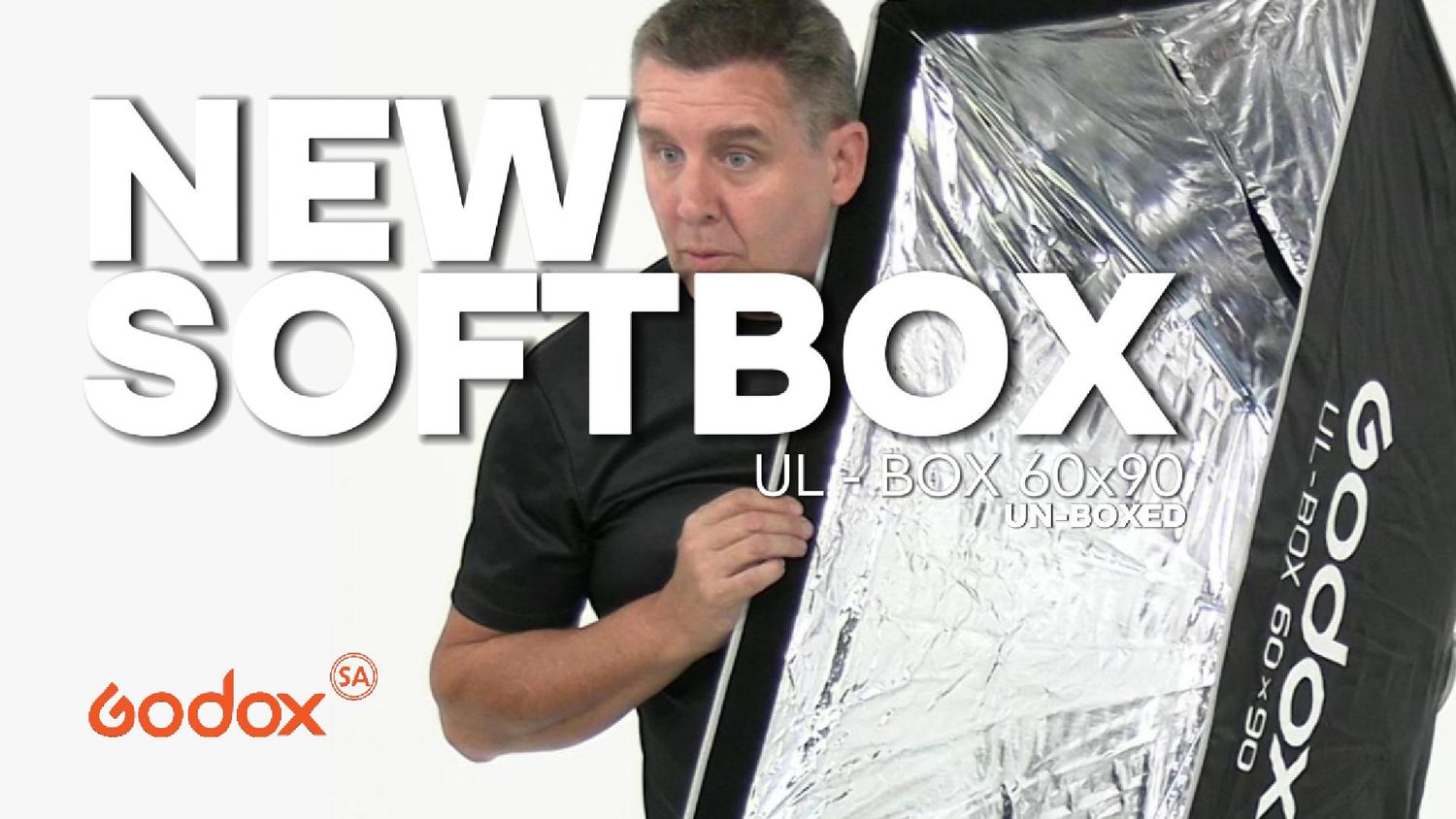 Man holding a Godox UL-BOX 30x90 softbox photography lighting accessory in a product review video.