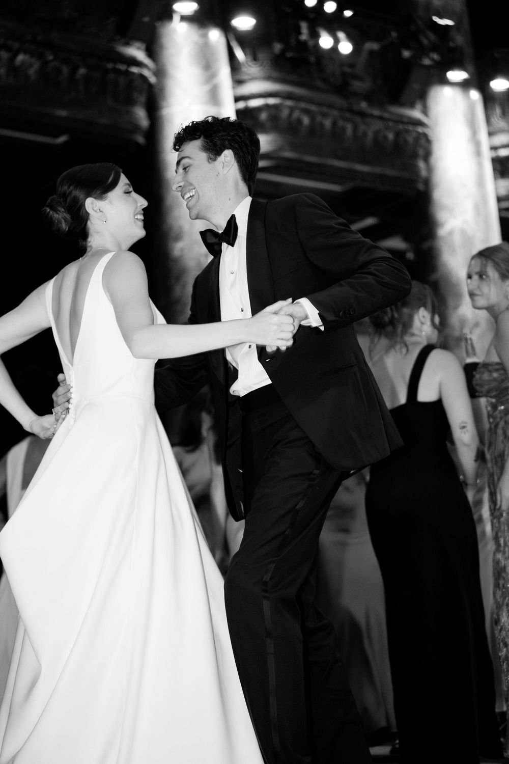 Black and white photo of a bride and groom sharing their first dance at an elegant wedding reception.