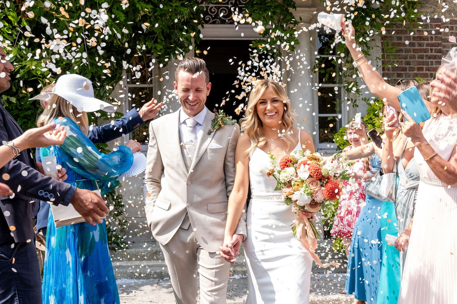 A couple in wedding attire walks together through a lush garden setting during their Islington ceremony.