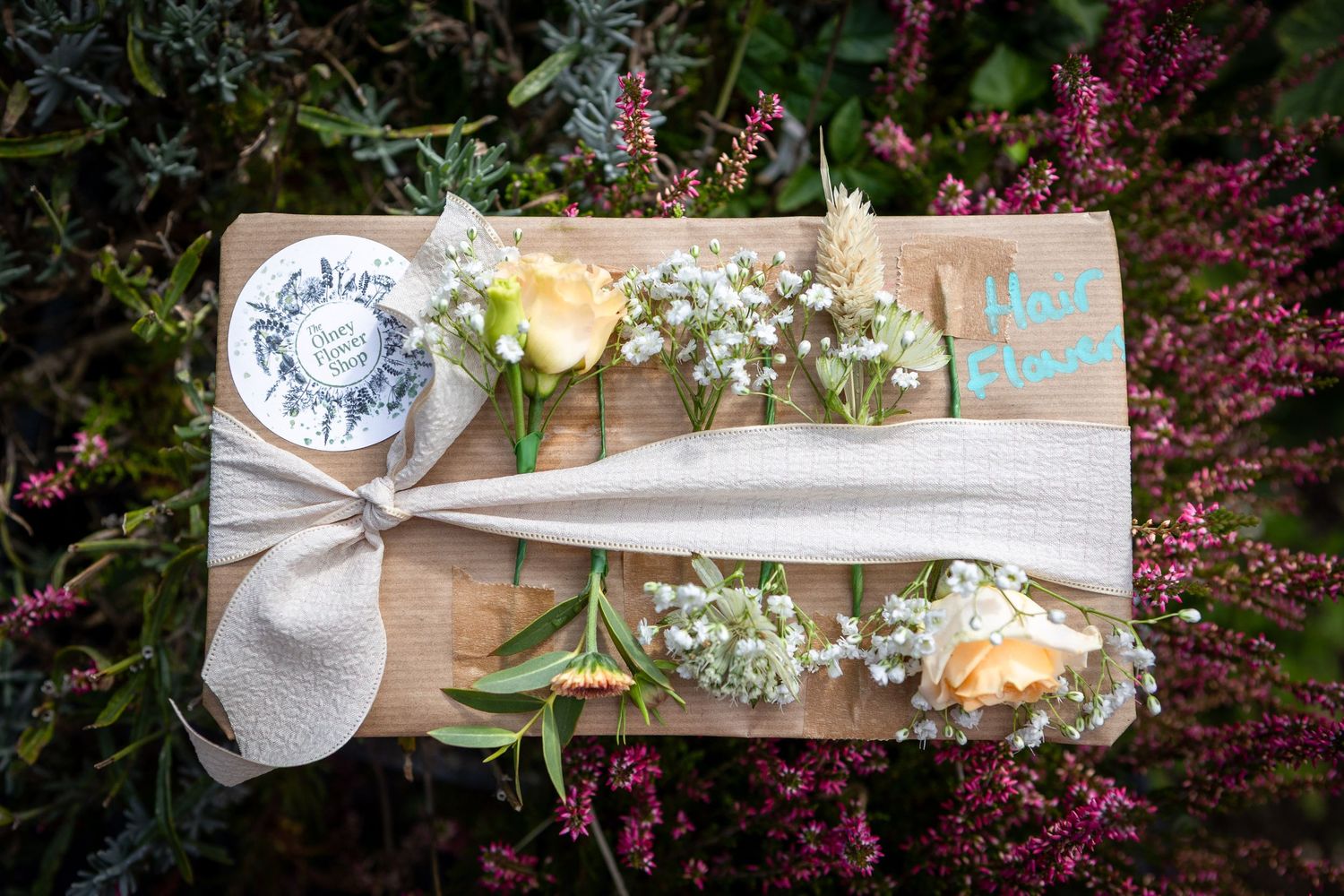 Boutonniere and corsage flowers with baby's breath arranged on a wooden board with ribbon.