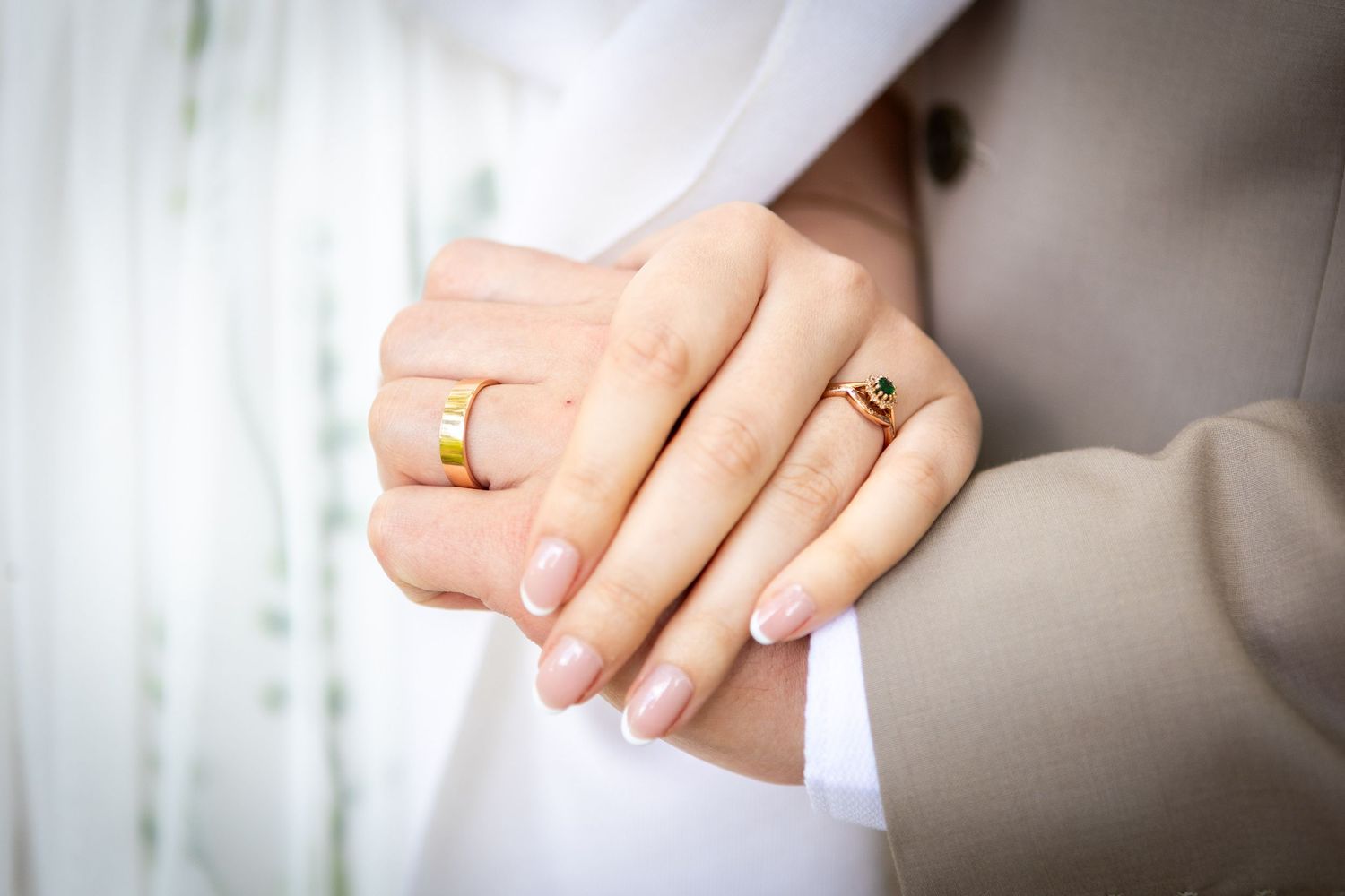 Close-up of bride and groom's hands showing gold wedding bands after their ceremony.