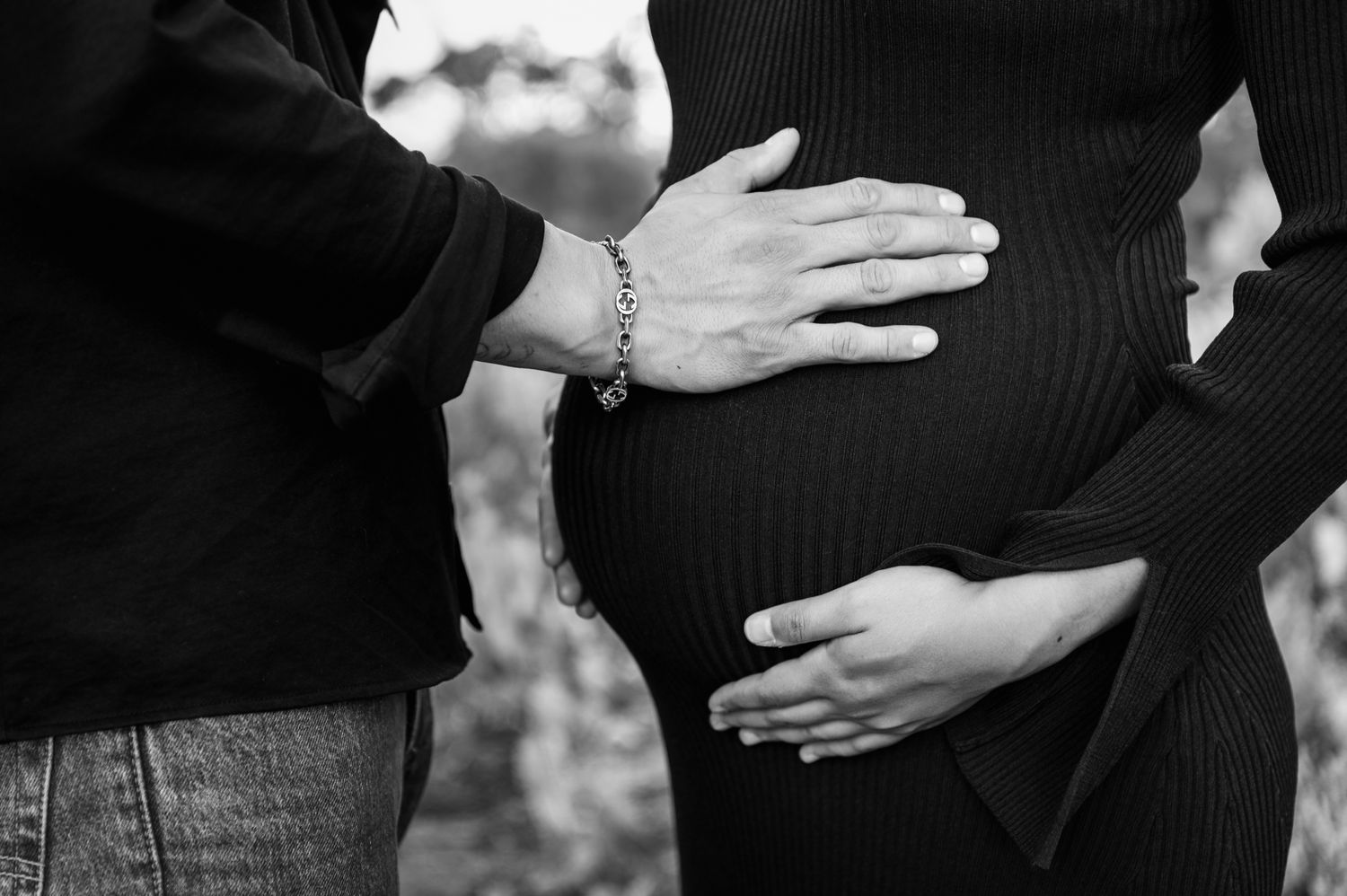 Pregnant woman in black dress posing outdoors in Australian outback landscape at golden hour.