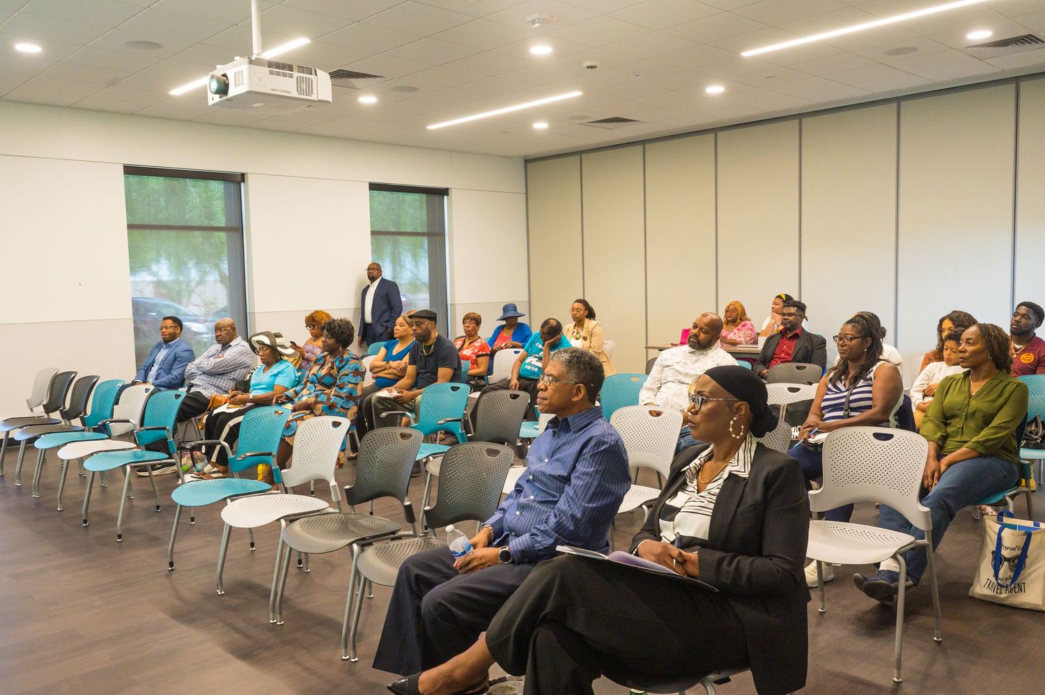 Diverse audience seated in modern conference room attentively listening to a presentation.