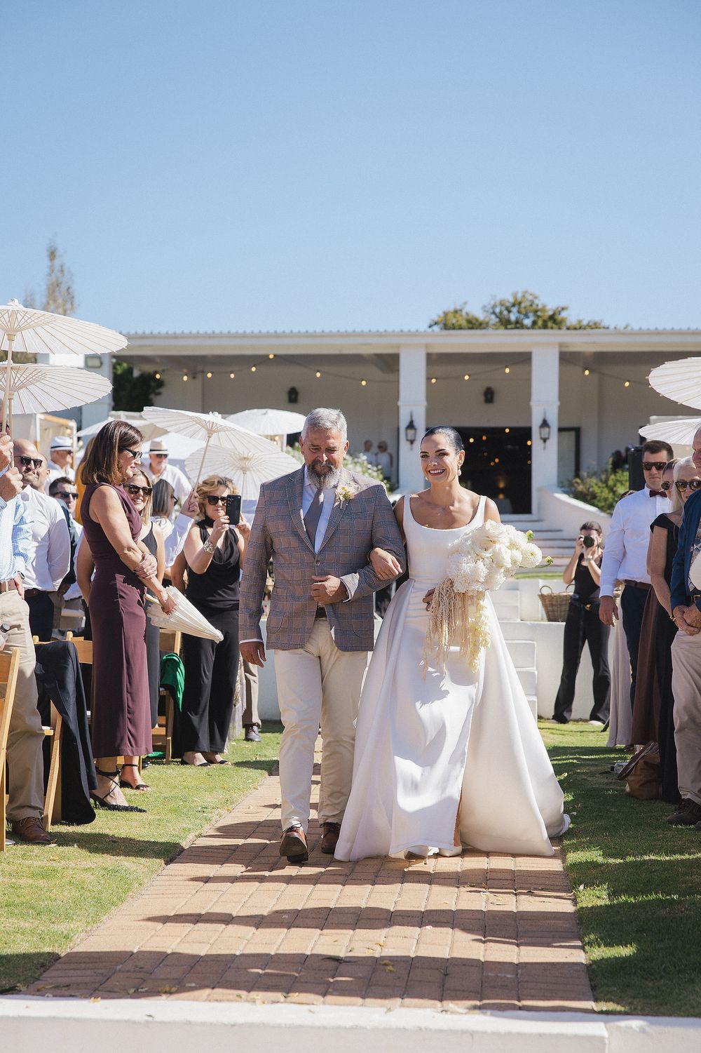 Romantic wedding aisle lined with guests and umbrellas