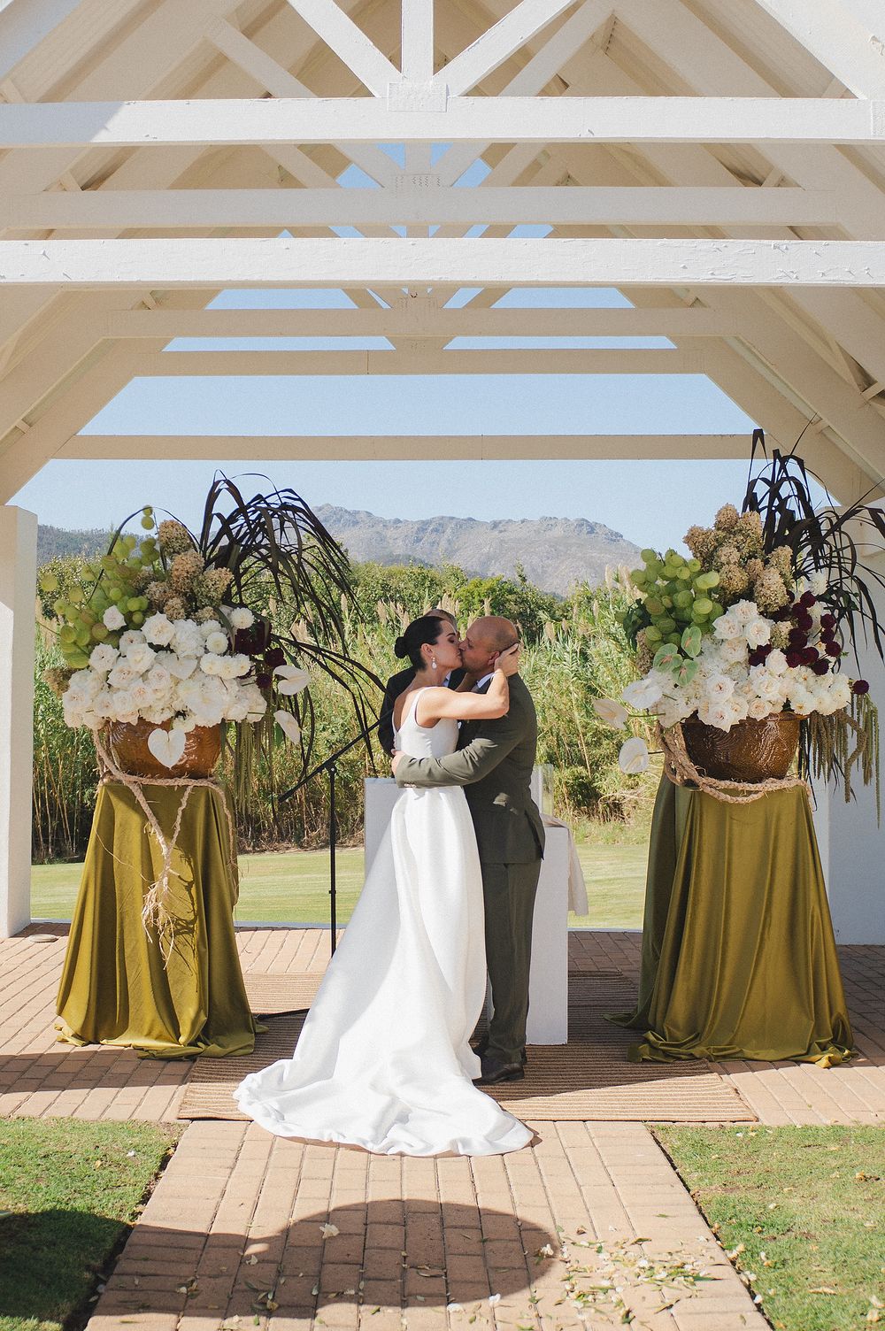 Bride and groom standing together beneath breathtaking vineyard and mountain views