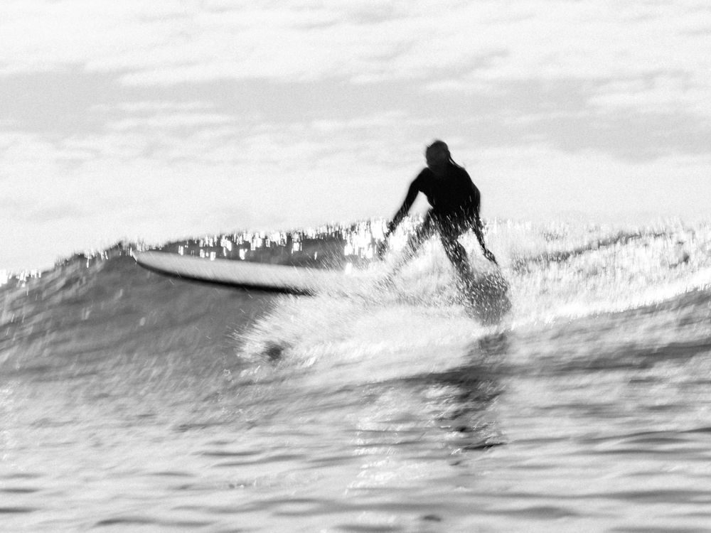 long exposure black and white image girl setting up a longboard turn at Blacksmiths Beach Newcastle, NSW