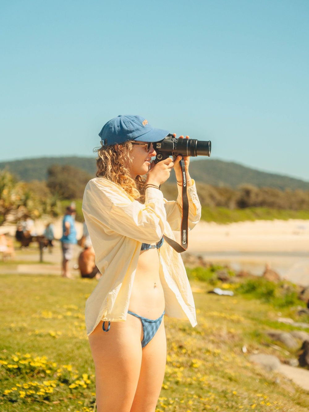 Candid portrait of a girl taking a photo of surfers at Crescent Head, NSW wth film like colours of the Australian summer